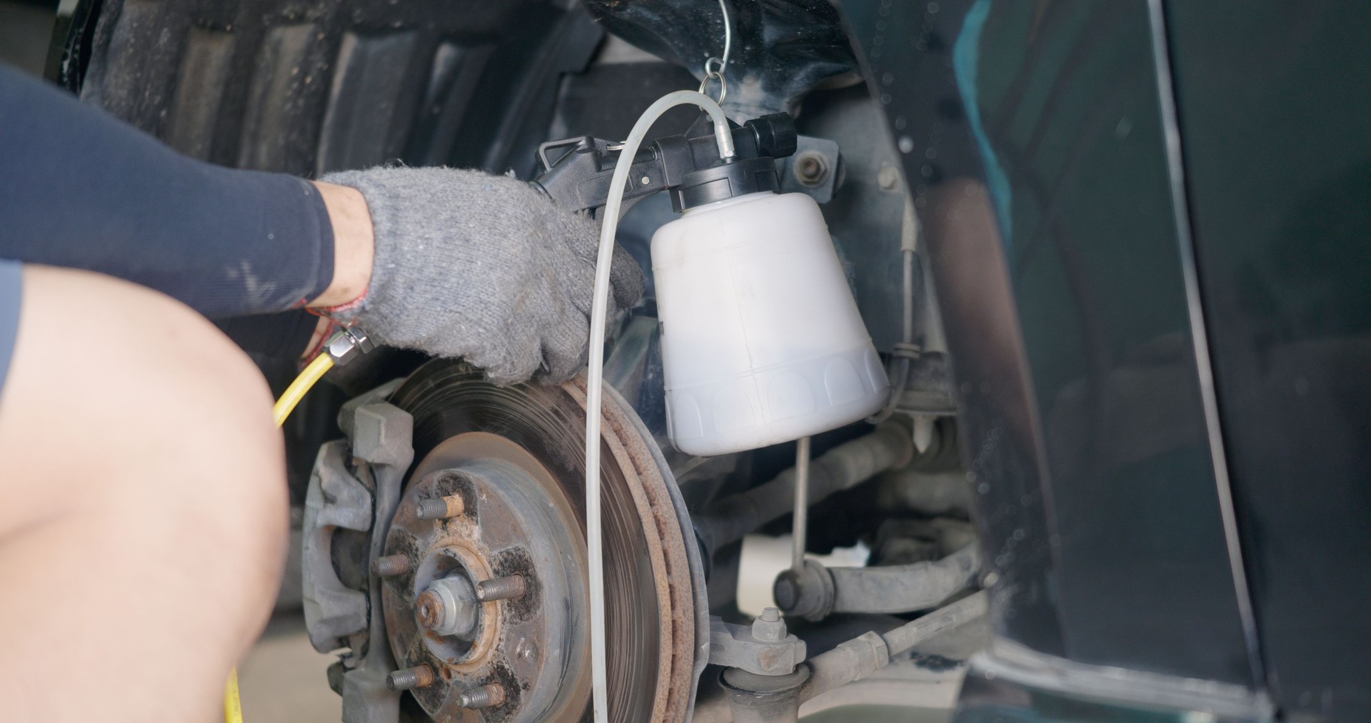 Auto mechanic replacing brake fluid on a vehicle